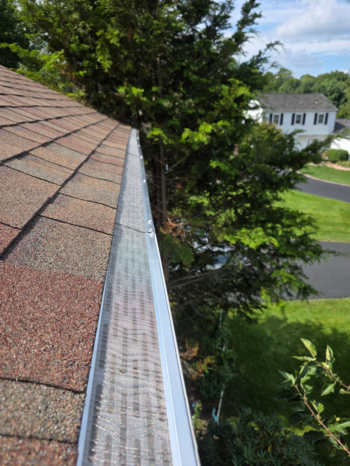 Close view of stainless-steel micro-mesh gutter guards installed edge to edge on a local home