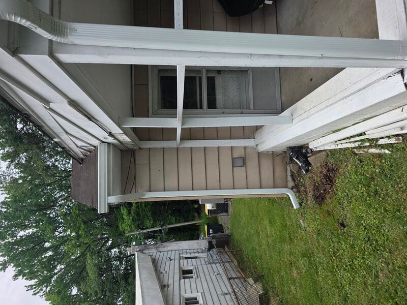 White downspout installed at the edge of a porch with bottom discharge