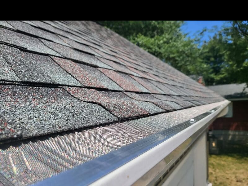 Close-up of micro-mesh gutter guard secured with mounting screw during a real install